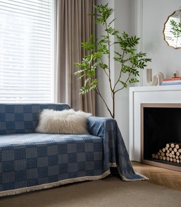 Detail of dark blue geometric jacquard sofa cover with fringe trim and woven texture