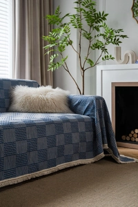 Detail of navy blue woven sofa cover featuring geometric white stripes and fringe edges