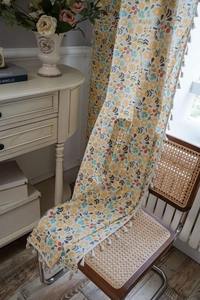 Detail view of cotton linen floral curtain fabric with delicate white tassel fringe trim