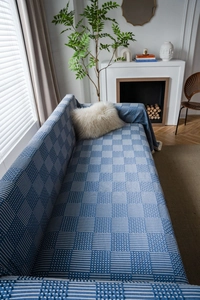 Close-up of blue and white geometric knit sofa cover with fringe details and soft texture