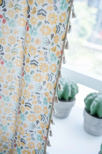 Close-up of floral print cotton linen curtain with elegant beige tassel fringe details