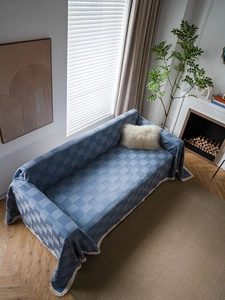 Close-up of blue geometric jacquard sofa throw with white tassel fringe detailing