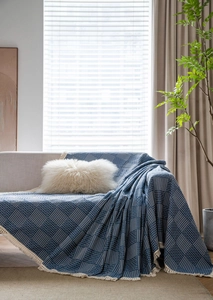 Detail of blue geometric jacquard sofa cover with thick fabric and white tassels