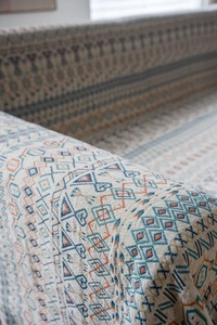 Dettaglio del copridivano in jacquard spesso con motivi geometrici boho e rossi