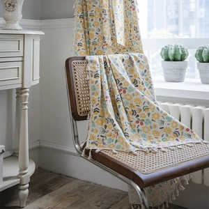 Floral cotton linen kitchen curtain with tassels draped on a vintage wicker chair