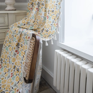 Floral cotton linen curtain with tassel trim displayed on a woven chair in a warm room