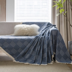 Blue geometric jacquard sofa throw blanket with white tassels on a cozy sofa