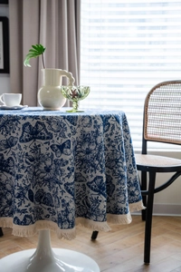 Close-up of blue and white floral jacquard tablecloth with elegant cream fringe edges