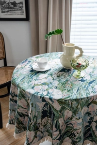 Detailed close-up of green floral jacquard tablecloth with thick white fringe border