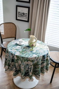 Close-up of green floral jacquard tablecloth with fringe details in home setting