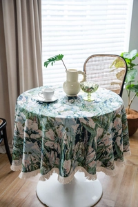 Close-up of green floral jacquard round tablecloth with decorative white fringe edges
