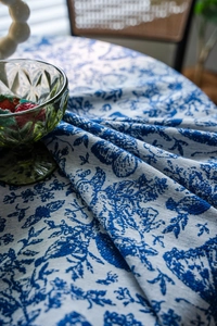Detail of blue and white Toile de Jouy floral pattern on textured woven tablecloth
