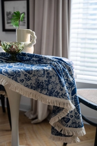 Macro detail of blue floral jacquard tablecloth with elegant beige fringe trim