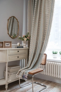 Detail of bohemian geometric jacquard curtain fabric with decorative fringe accents