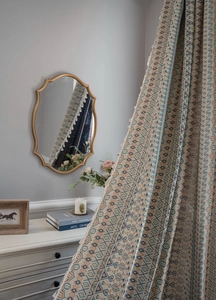 Detailed view of geometric jacquard fabric curtains with elegant cream fringe edges