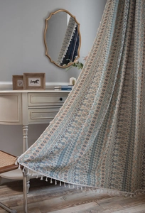 Detail of bohemian geometric jacquard curtain fabric with white tassels and cotton-linen texture