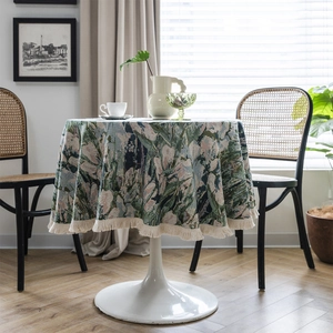 Vintage green jacquard round tablecloth with tassel edge on a table with tulips