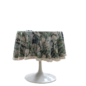 Green jacquard floral round tablecloth with elegant beige fringe on white table