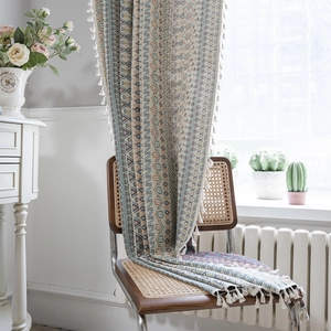 Ethnic geometric jacquard curtain with tassels displayed on a vintage rattan chair