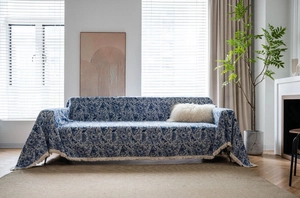 Detailed close-up of blue butterfly floral sofa cover with elegant white fringe tassels