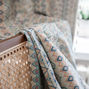 Bohemian geometric jacquard throw blanket with white tassels on a vintage chair