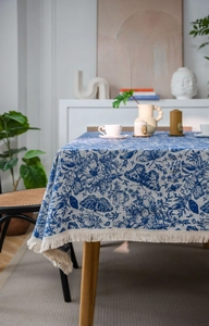 Detail der blau geblümten Jacquard-Tischdecke mit eleganten cremefarbenen Quastenfransen