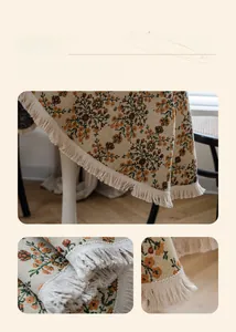 Detail of vintage floral tablecloth featuring elegant orange patterns and white tassels