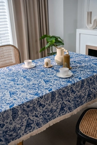 Detail der blau-weißen Tischdecke mit Schmetterlingsmuster und eleganten weißen Fransen