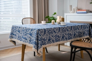 Detail der blau-floralen Tischdecke mit Schmetterlingsprint und weißen Fransen