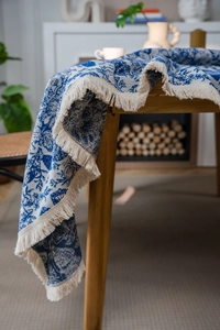 Nahaufnahme der blau-weißen Jacquard-Tischdecke mit cremeweißen Fransen an den Kanten