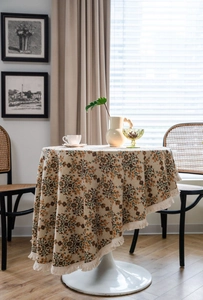 Close-up of floral jacquard tablecloth fabric with delicate cream tassel fringe edges