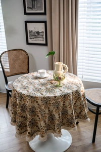 Macro shot of retro floral patterned round tablecloth featuring delicate fringe trim edge
