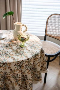 Macro detail of round floral tablecloth with vintage jacquard texture and white fringe trim