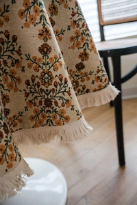 Detailed close-up of retro floral jacquard tablecloth with elegant cream tassels