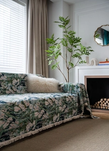 Close-up of vintage green floral jacquard sofa throw with elegant fringe details