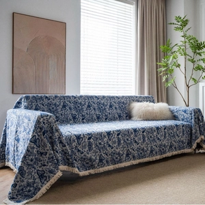 Blue and white butterfly jacquard sofa cover with fringe in a cozy living room setting