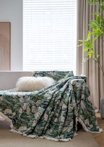 Detail of green floral jacquard sofa throw with elegant tassels in a cozy home setting