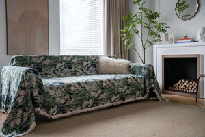 Close-up of vintage green floral jacquard sofa throw with elegant fringe edge details