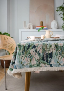 Close-up of thick floral jacquard tablecloth with elegant cream fringe tassels