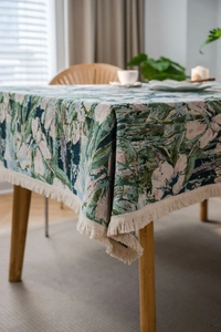 Detail of green floral jacquard tablecloth with rustic bohemian tassels and woven texture