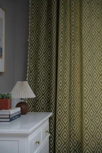 Detail of green and white diamond pattern curtain with elegant white tassel fringe