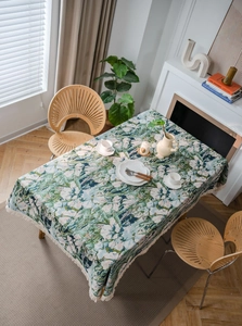 Detail of floral jacquard tablecloth with bohemian fringe edges and botanical patterns