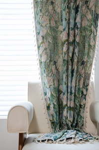 Detailed close-up of green floral jacquard fabric with elegant cream fringe tassels