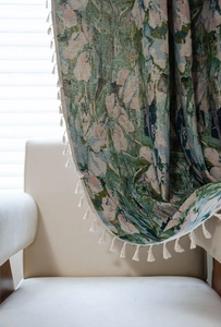 Close-up of green floral jacquard fabric with tassels draped on a white chair