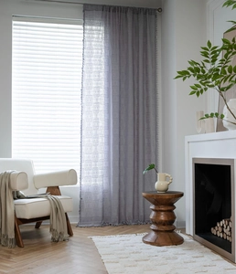 Detailed view of grey crochet lace curtain with geometric patterns and tassel trim