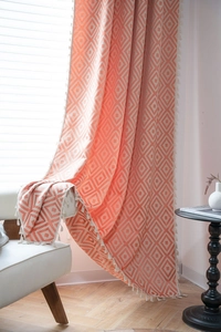 Detailed texture of coral pink geometric diamond pattern curtain with white tassel fringe