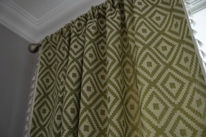 Detail of green geometric pattern curtain with white decorative tassel trim edge