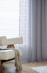 Detail of grey crochet lace curtain with geometric embroidery and tassel fringe edges