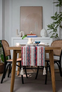 Ethnic geometric print table runner with cream tassels on a rustic wooden dining table