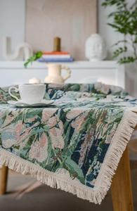 Detail of woven jacquard table runner featuring vintage garden landscape and cream tassels